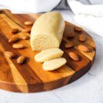Sliced roll of homemade marzipan on a wooden cutting board.