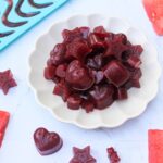 Dark pink fruit gummies on a small plate.
