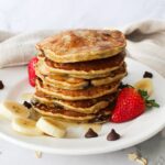 Stack of fluffy chocolate chip pancakes on a plate.