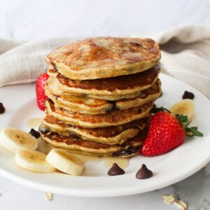 Stack of fluffy chocolate chip pancakes on a plate.